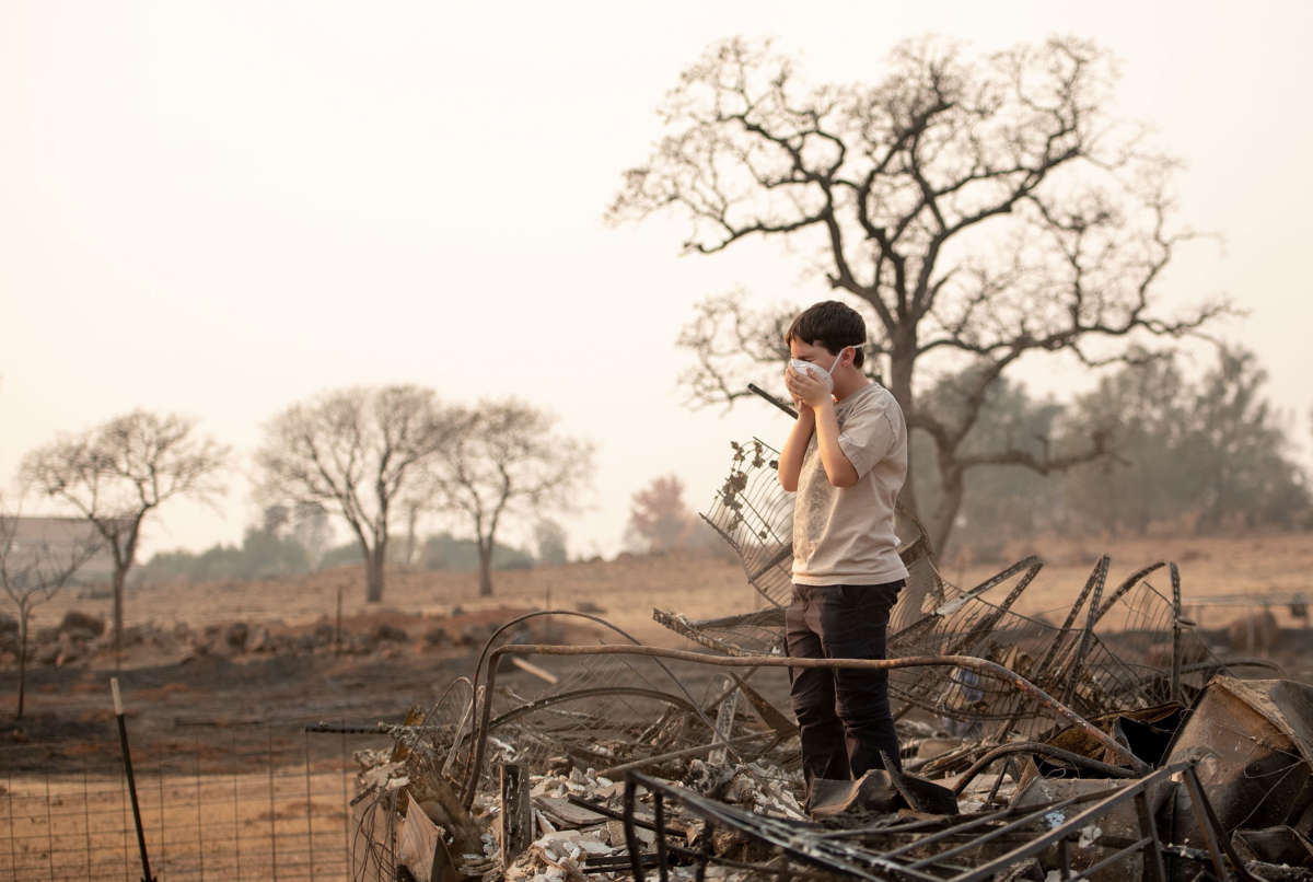 A child adjusts his face mask while searching through the burned remains of his home in Paradise, California, on November 18, 2018.