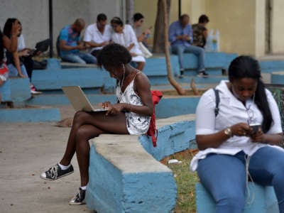 People use their mobile phones and laptops to connect to the internet at a park in Havana, Cuba, on December 5, 2018.