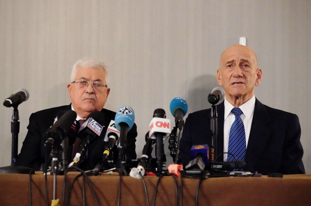 Palestinian president Mahmud Abbas and Former Israeli Prime Minister Ehud Olmert sit at a podium