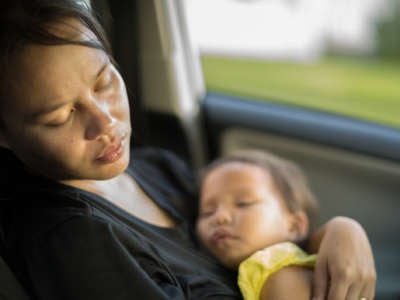 A mother holds her baby in the backseat of a moving car
