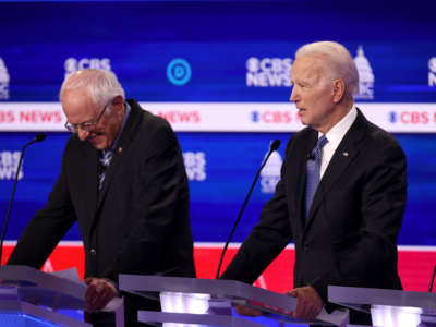 Sen. Bernie Sanders giggles at his podium as Former Vice President Joe Biden speaks