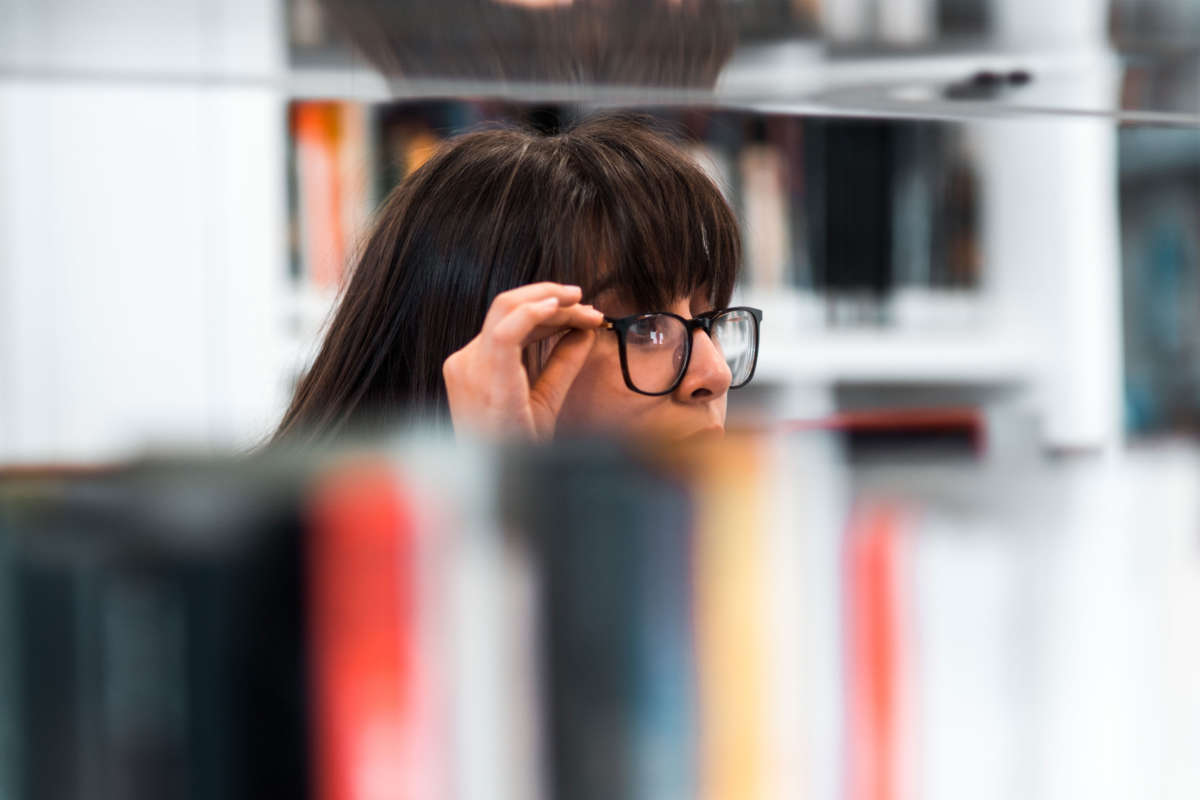 A person looks over shelves of books in a library