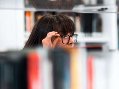 A person looks over shelves of books in a library