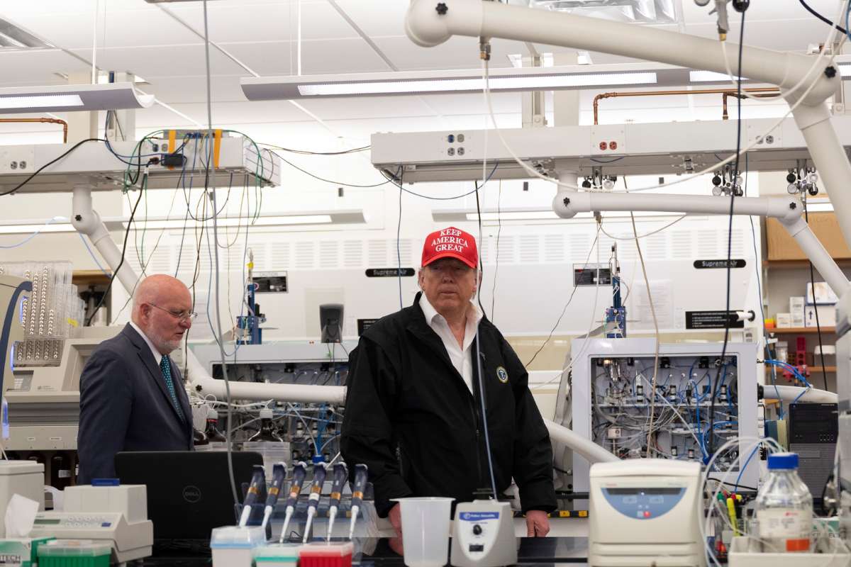 Donald Trump stands inside of a laboratory wearing a red maga hat