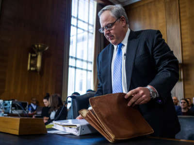 David Bernhardt packs papers into his briefcase during a hearing