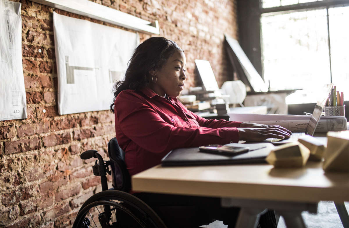 A woman in a wheelchair works on a computer