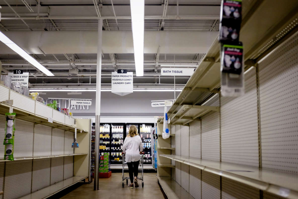 A woman leaves an empty aisle in a grocery store