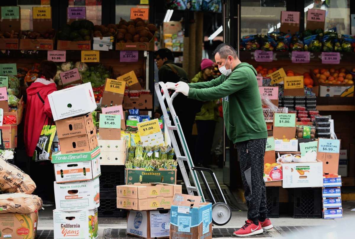 A worker stocks up on groceries at a local supermarket on March 20, 2020, in the Brooklyn borough of New York.