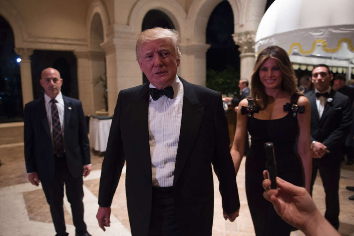 Then-President-elect Donald Trump answers questions from reporters accompanied by his wife Melania for a New Year's Eve party December 31, 2016, at Mar-a-Lago in Palm Beach, Florida.