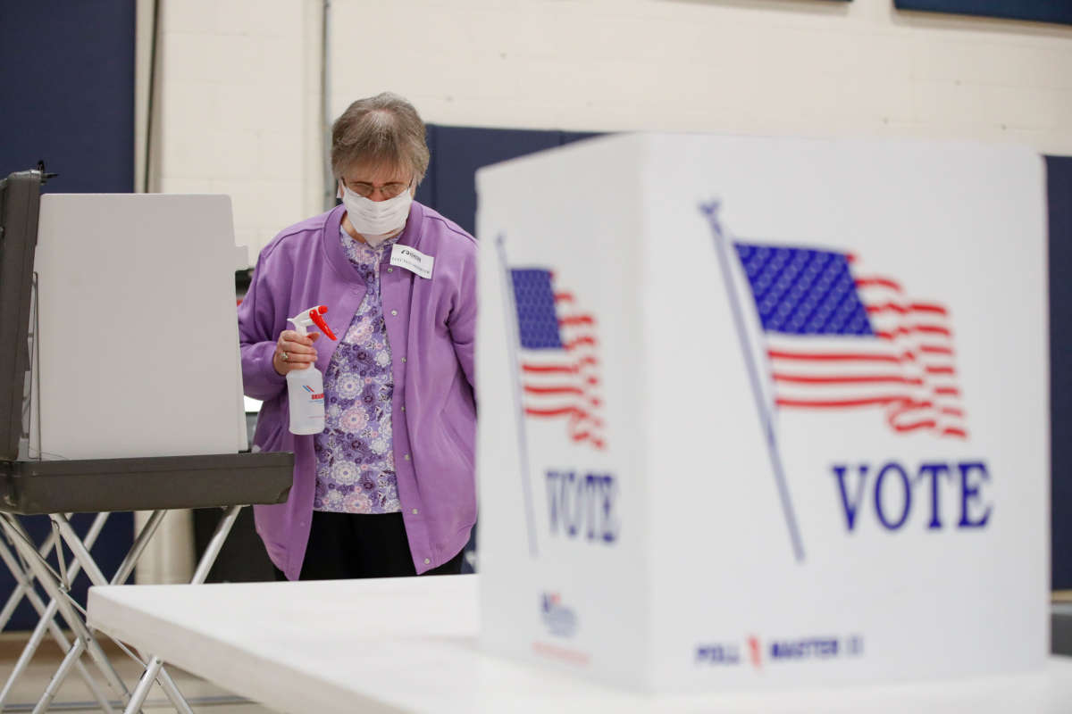 An election observer cleans voting booths during the Democratic presidential primary election at the Kenosha Bible Church gym in Kenosha, Wisconsin, on April 7, 2020.