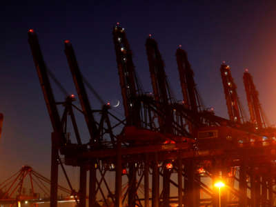 The waxing crescent moon is seen between dock levelers at a container terminal in the harbor of the northern German city of Hamburg on March 26, 2020. The lifeblood of globalization has been considerably affected over the course of the outbreak.