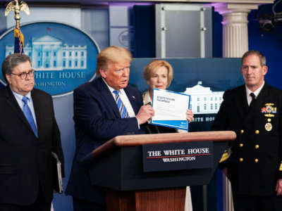 President Trump holds a copy of the president’s coronavirus guidelines brochure at a COVID-19 update briefing on March 23, 2020, in the James S. Brady Press Briefing Room of the White House.