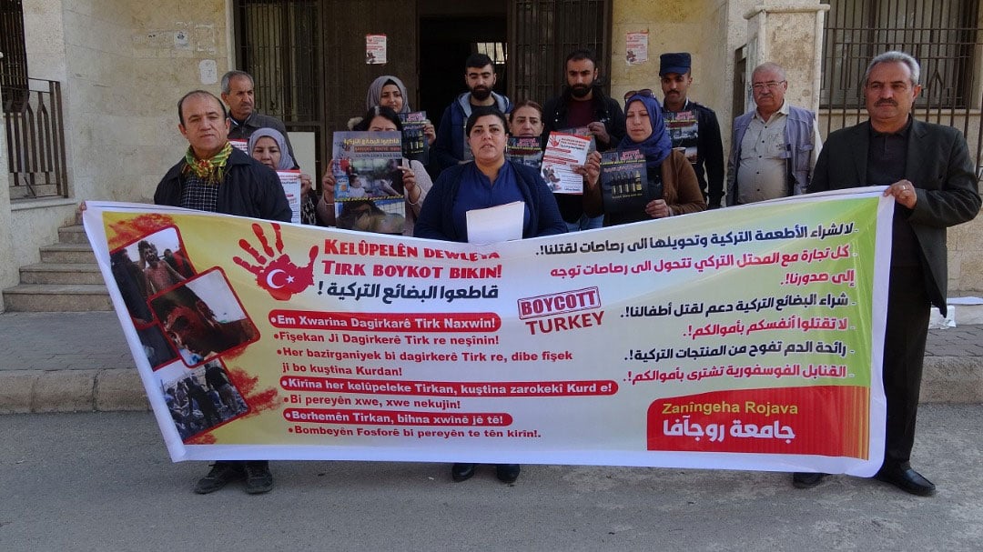 People in Derik, Rojava, hold a banner calling for a boycott of Turkish products.