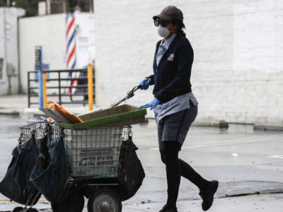 A U.S. Postal Service worker wears a mask and gloves while delivering mail near a Food Bank distribution for those in need, as the coronavirus pandemic continues, on April 9, 2020, in Van Nuys, California.