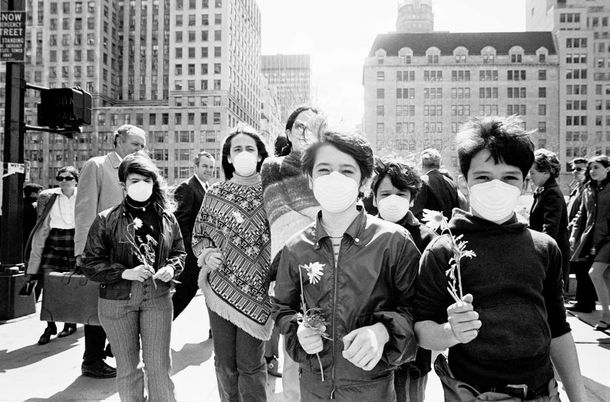 Vintage children wear face masks and hold flowers during a protest
