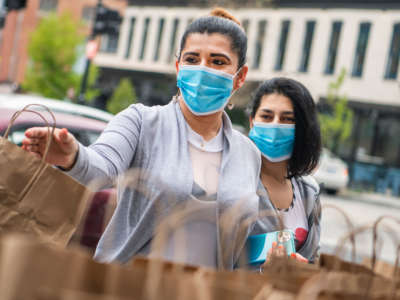 Restaurant industry workers affected by the coronavirus outbreak pick up donated food during a distribution organized by Saval Foodservice and Busboys and Poets at 14th and V Streets NW, on April 17, 2020.