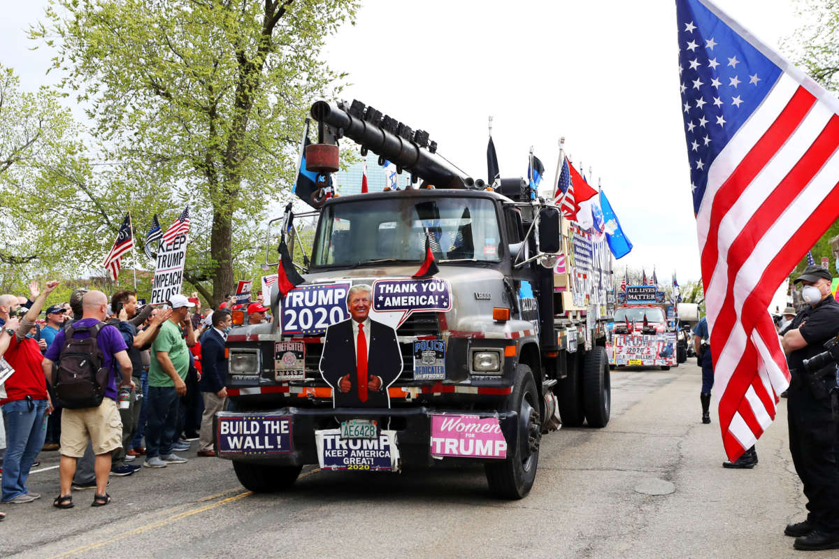 Trucks covered with President Trump signs drive down Beacon Street during a Reopen Massachusetts Rally outside of the Massachusetts State House on May 4, 2020 in Boston, Massachusetts.