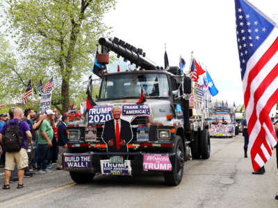 Trucks covered with President Trump signs drive down Beacon Street during a Reopen Massachusetts Rally outside of the Massachusetts State House on May 4, 2020 in Boston, Massachusetts.