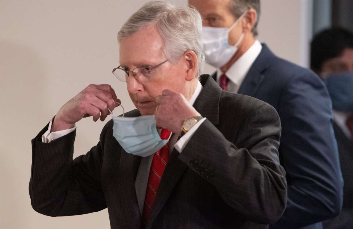 Senate Majority Leader Mitch McConnell removes a mask as he arrives to speak to the media on Capitol Hill in Washington, D.C., May 5, 2020.