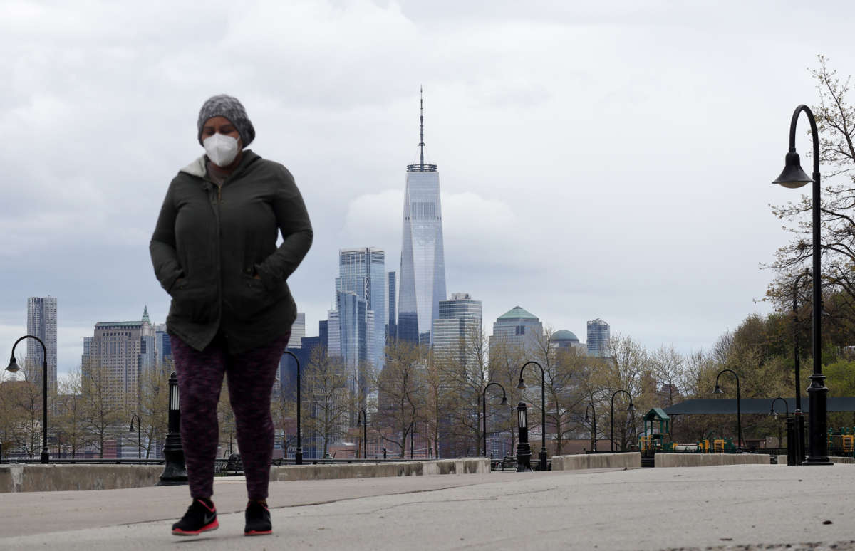 A person in a mask and a jacket walks through new york