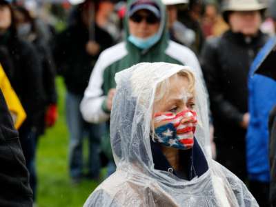 A woman with the u.s. flag painted on her face participates in a reopen protest
