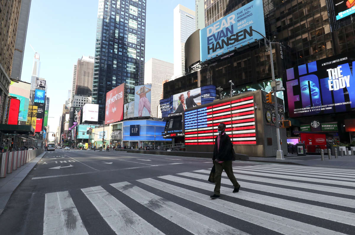 An improperrly-masked man walks across a deserted Time Square