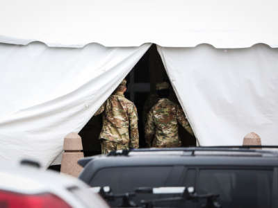 Military personnel step out of a tent set up at the back entrance to the Holyoke Soldiers home in Holyoke, Massachusetts, on March 3, 2020. Forty-seven had died of the virus at the state-run home for veterans as of April 17.