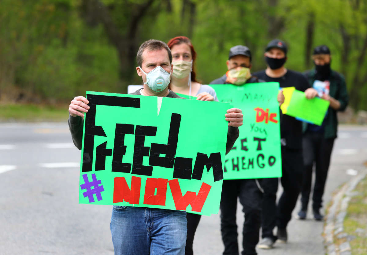After making three passes by the Lemuel Shattuck Hospital in their cars, some of the protesters walk back toward the hospital to speak to the media in Boston on May 17, 2020. People associated with Massachusetts Acting for Change Together (MassACT) staged a car caravan demonstration to protest the treatment of those in psychiatric hospitals and other group settings.
