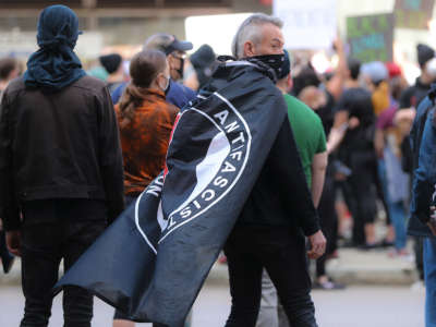 Hundreds of protesters gather at Government Center including a protester with an ANTIFA flag draped over his shoulders during a rally sponsored by the Youth of Greater Boston to demand justice for George Floyd and support of the Black Lives Matter movement in Boston on May 31, 2020.