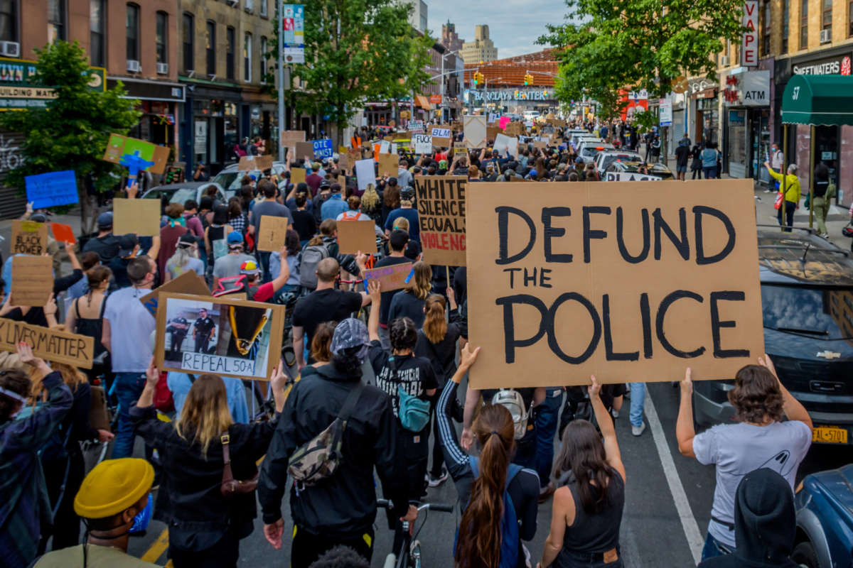 Participants hold a "Defund The Police" sign at the protest, on June 2, 2020. Thousands of protesters filled the streets of Brooklyn in a massive march to demand justice for George Floyd.