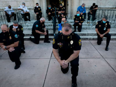 Police officers kneel during a rally in Coral Gables, Florida, on May 30, 2020, in response to the recent death of George Floyd.