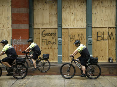 Police ride bikes past a boarded up store during a march against police brutality and racial justice on June 11, 2020, in New York City.