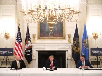 President Donald Trump speaks as Gov. Pete Ricketts (left) and Governor Kevin Stitt listen during a roundtable at the State Dining Room of the White House on June 18, 2020, in Washington, D.C.