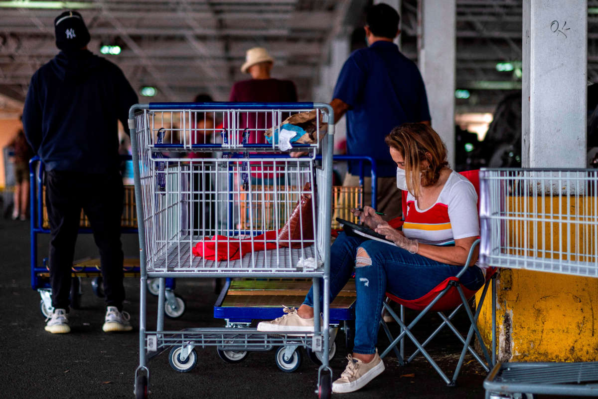 People wear face masks as they queue at a supermarket during a mandatory confinement to counter the new coronavirus in Carolina, Puerto Rico, on April 7, 2020.