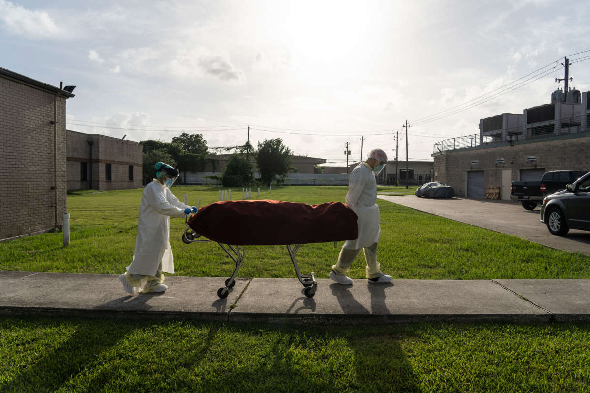 Medical staff wearing full PPE push a stretcher with a deceased patient to a car outside of the COVID-19 intensive care unit at the United Memorial Medical Center on June 30, 2020, in Houston, Texas.