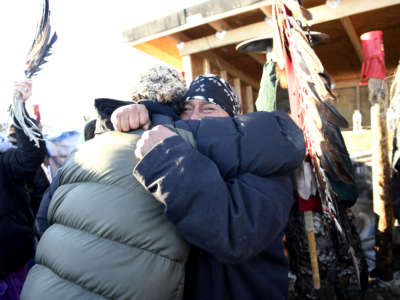 Two people tearfully embrace in cold weather gear