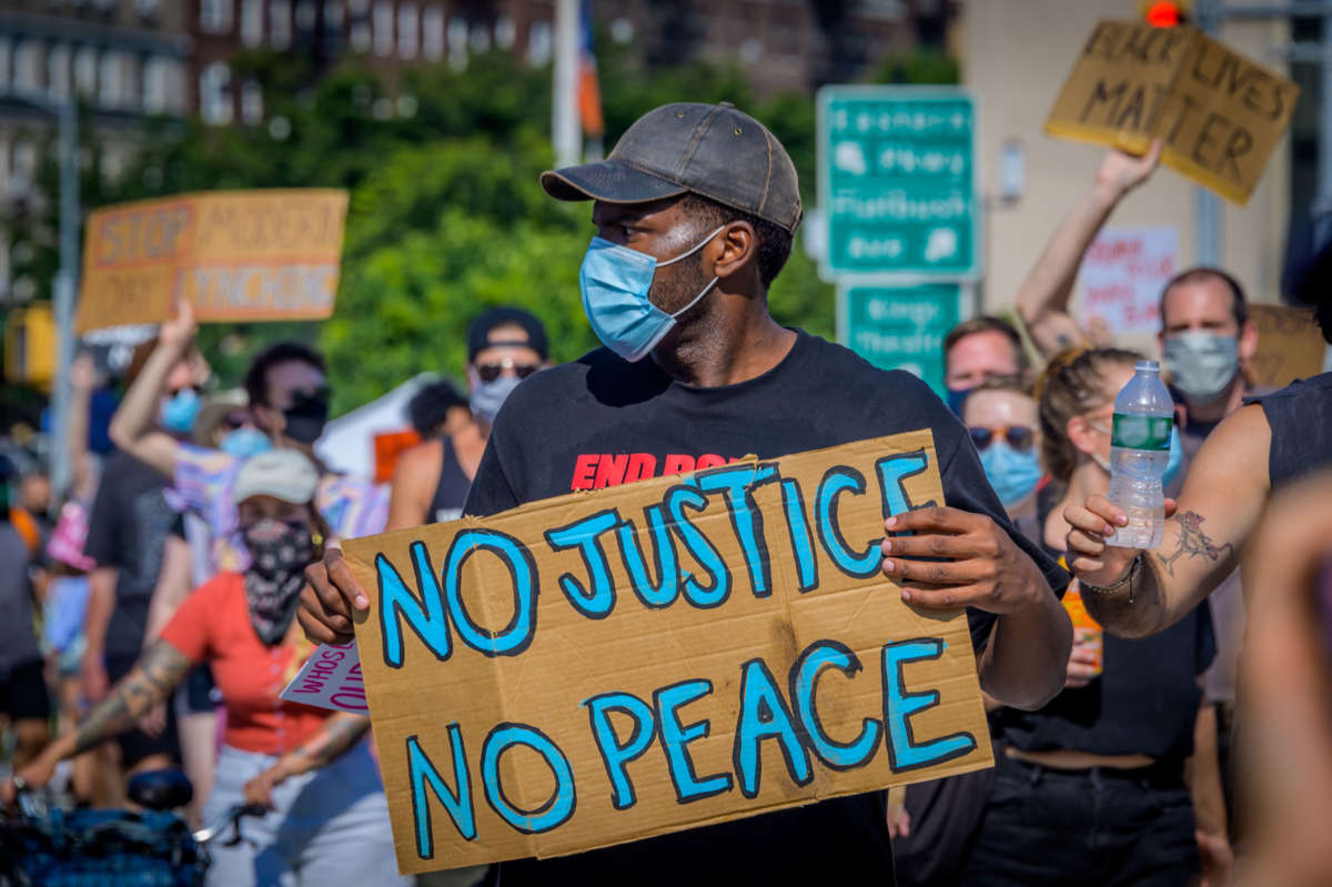 A participant holds a No Justice No Peace sign at a protest in Brooklyn, New York, July 4, 2020.