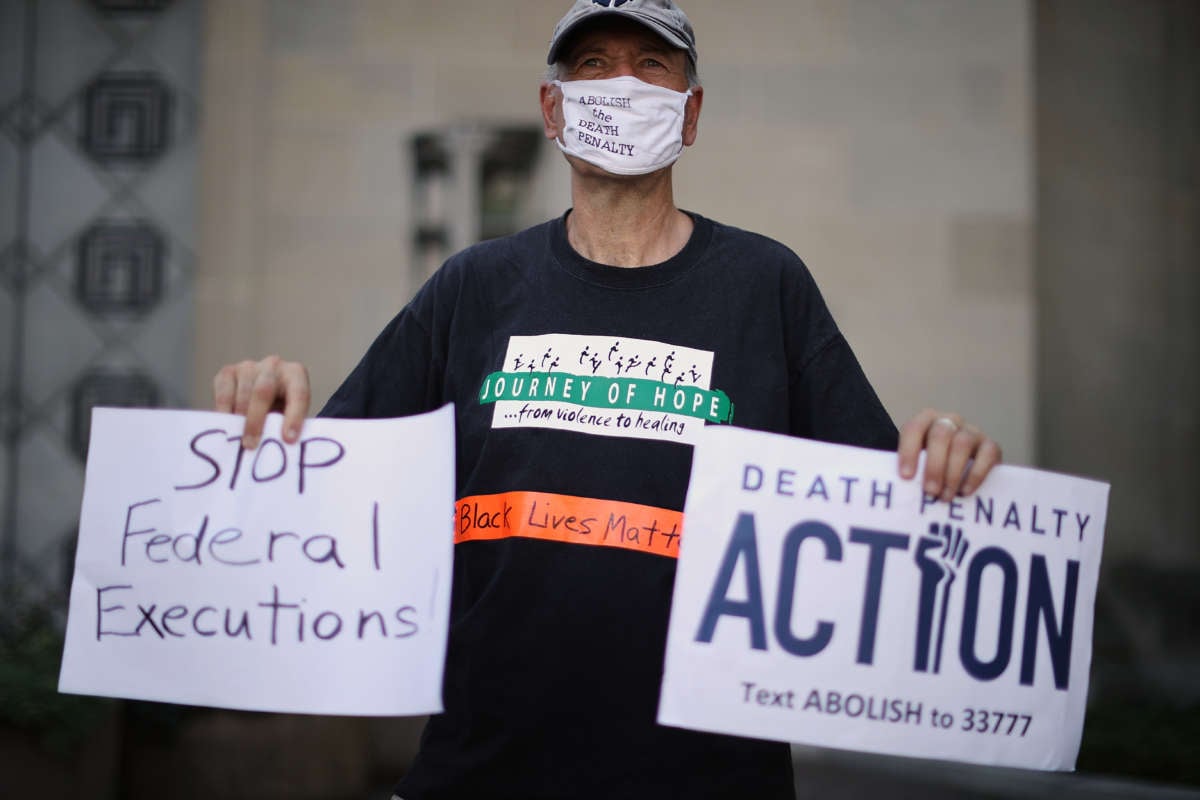An elderly man holds signs opposing the death penalty