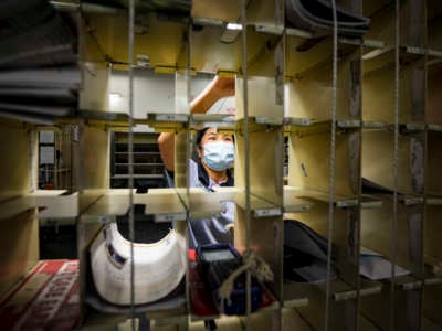 A postal worker puts mail into cubbies