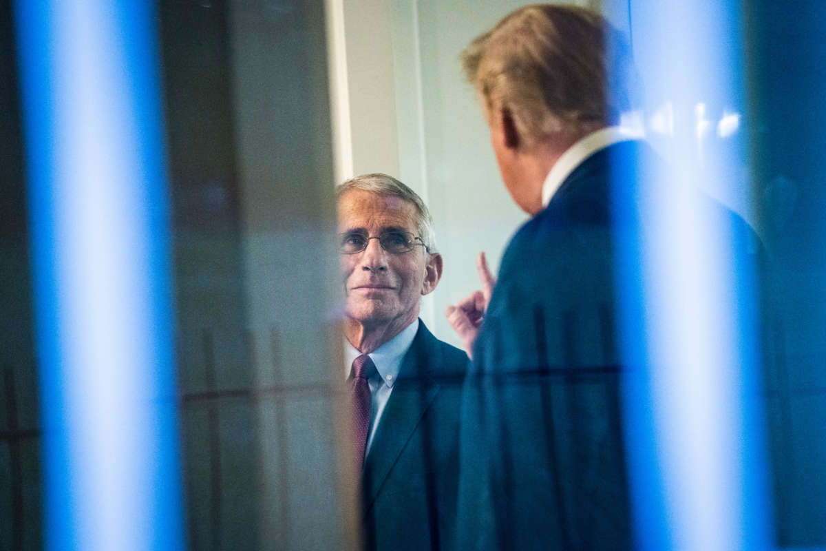 President Trump, seen through a window, speaks with Dr. Anthony Fauci, director of the National Institute of Allergy and Infectious Diseases, in the press office at the White House on April 22, 2020, in Washington, D.C.