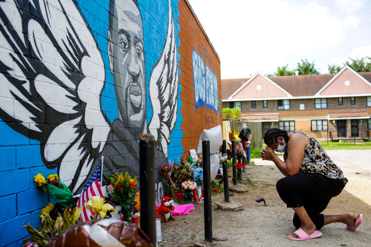 A woman prays outside Scott Food Mart at a makeshift memorial and a mural for George Floyd in the 3rd Ward on June 9, 2020, in Houston, Texas.