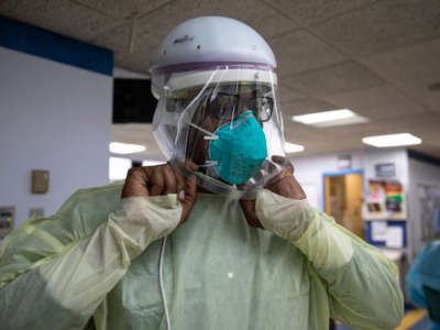 A respiratory nurse puts on a powered air purifying respirator helmet before treating a COVID-19 patient on the Medical Intensive Care Unit floor at the Veterans Affairs Medical Center, April 24, 2020, in New York City.