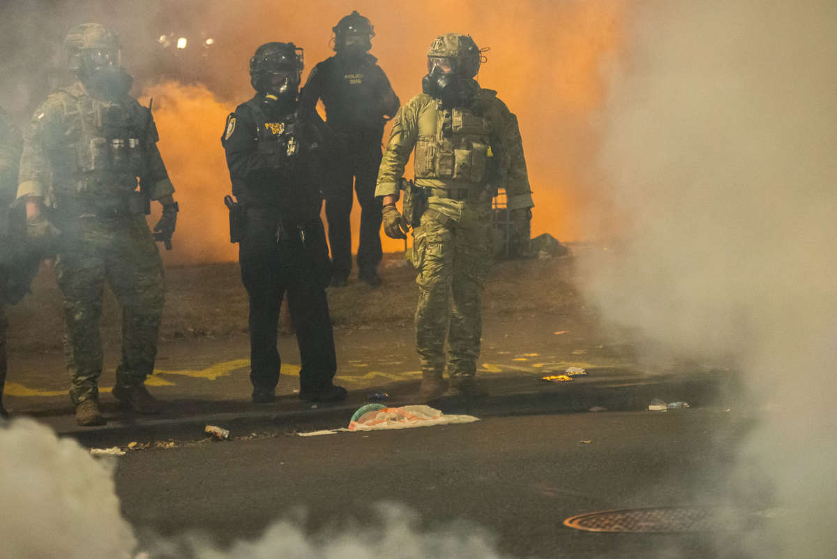 federal police walk through clouds of tear gas that they'd recently shot at protesters
