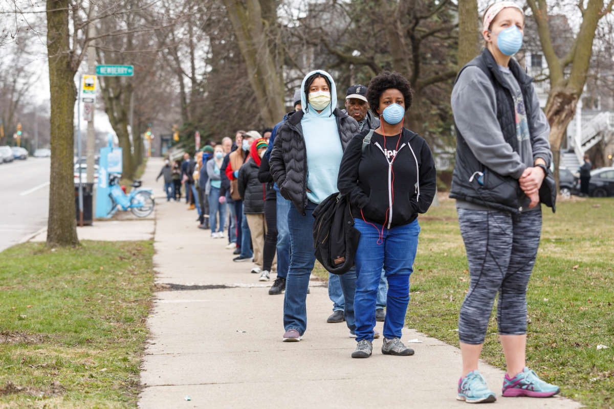 Voters in masks wait in a line, outside and in cold weather outerwear, to vote in Wisconsin