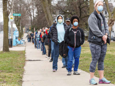 Voters in masks wait in a line, outside and in cold weather outerwear, to vote in Wisconsin
