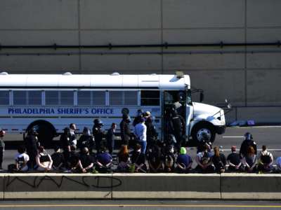 Arrested protesters stand and sit on a barrier of the Vine Street Expressway after police shot tear gas to disperse the crowd on June 1, 2020, in Philadelphia, Pennsylvania.