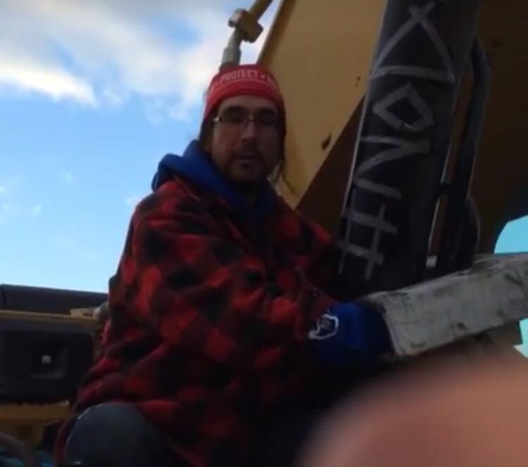 Dene Water Protector Daniel T’seleie locking down on an excavator in a “Sleeping Dragon” to disrupt the construction of the Dakota Access Pipeline on September 14, 2016.