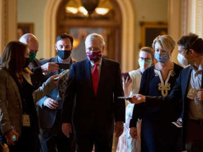 Senate Majority Leader Mitch McConnell talks with reporters as he walks from the Senate floor after a vote to his office on July 30, 2020.