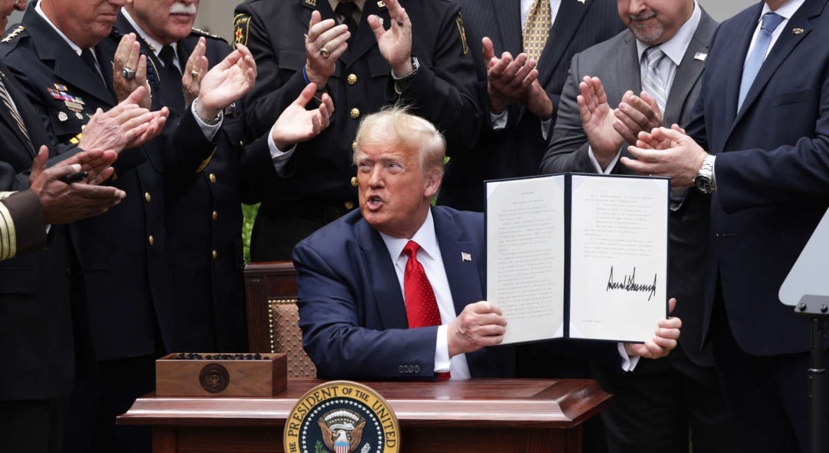 Surrounded by members of law enforcement, President Trump holds up an executive order he signed on “Safe Policing for Safe Communities” during an event in the Rose Garden at the White House, June 16, 2020, in Washington, D.C.