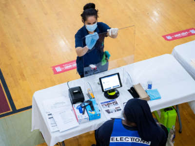A worker cleans an election officials station during early voting for the June 2 primary at McKinley Technology High School in Washington, D.C., on May 26, 2020.
